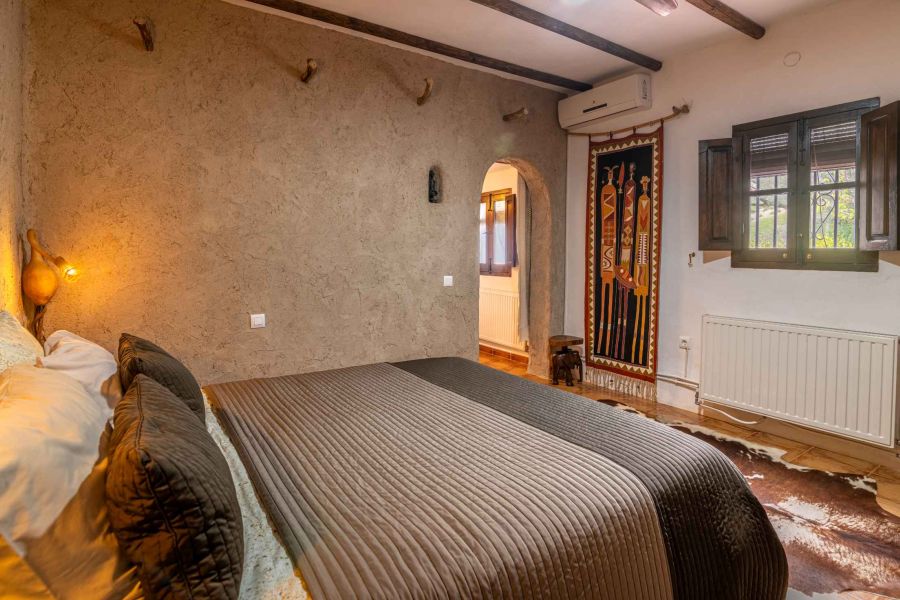 lit confortable dans une chambre à la décoration ethnique donnant sur une oliveraie