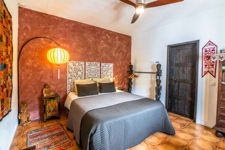 lit confortable dans une chambre à coucher décorée de façon ethnique, avec ventilateur et air conditionné