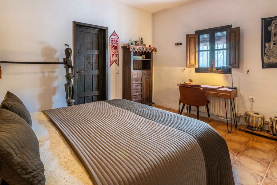 tweepersoonbed in ruime kamer met schrijftafel en zicht op olijfgaard